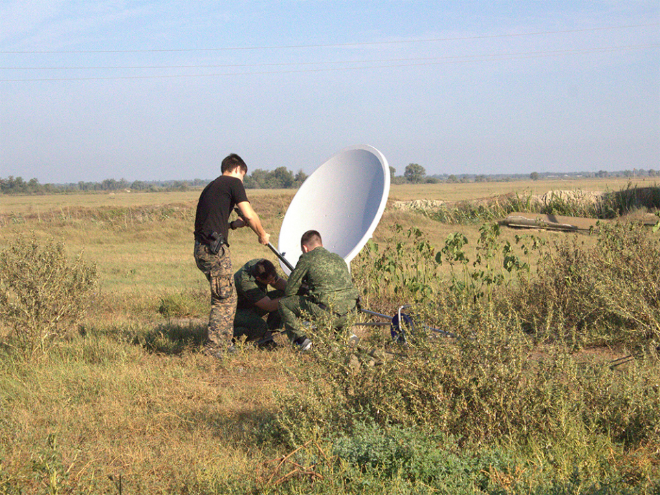 Сотрудники группы связи настраивают спутниковую антенну